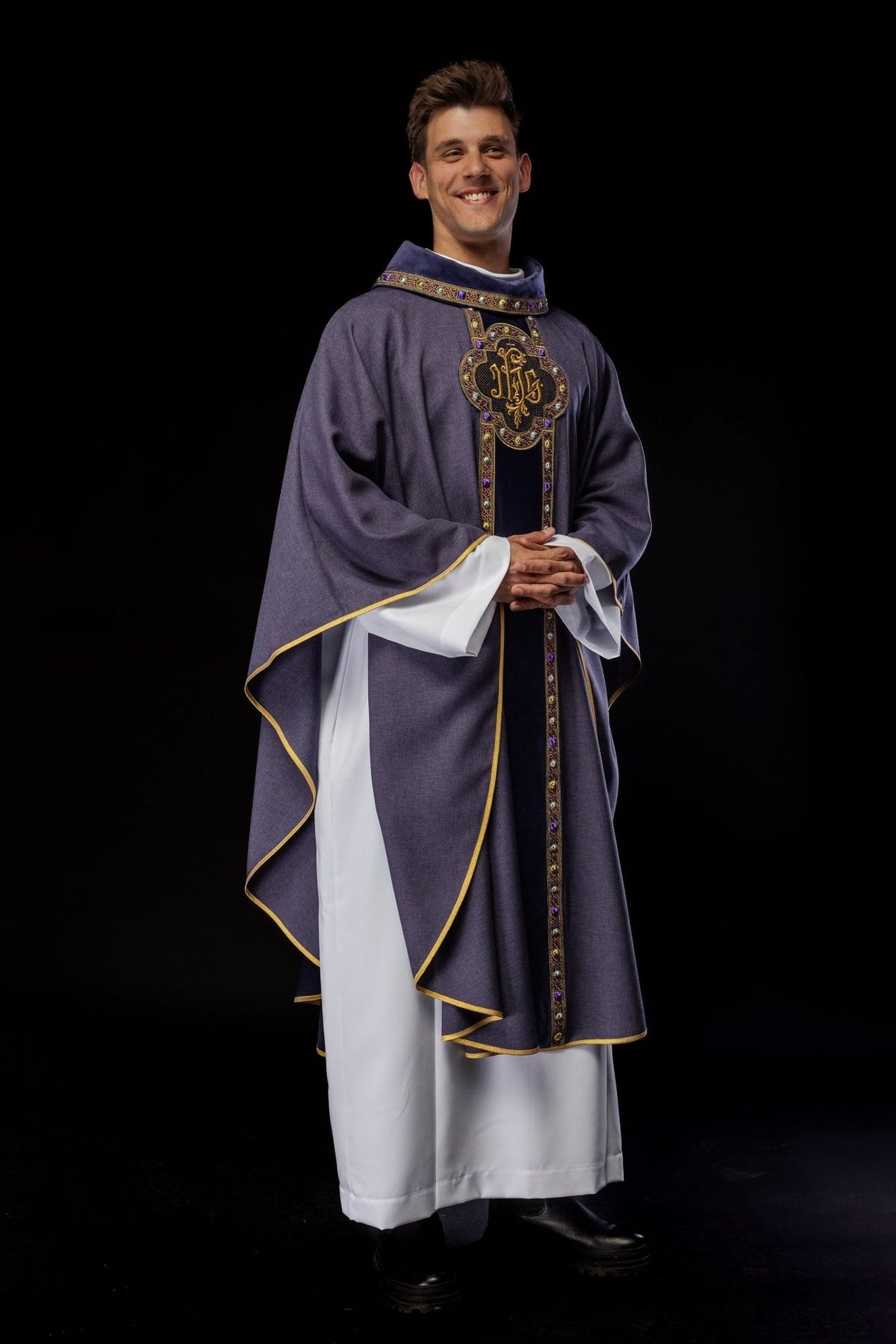 Purple chasuble worn angled front view with embroidered IHS orphrey and flowing sleeves