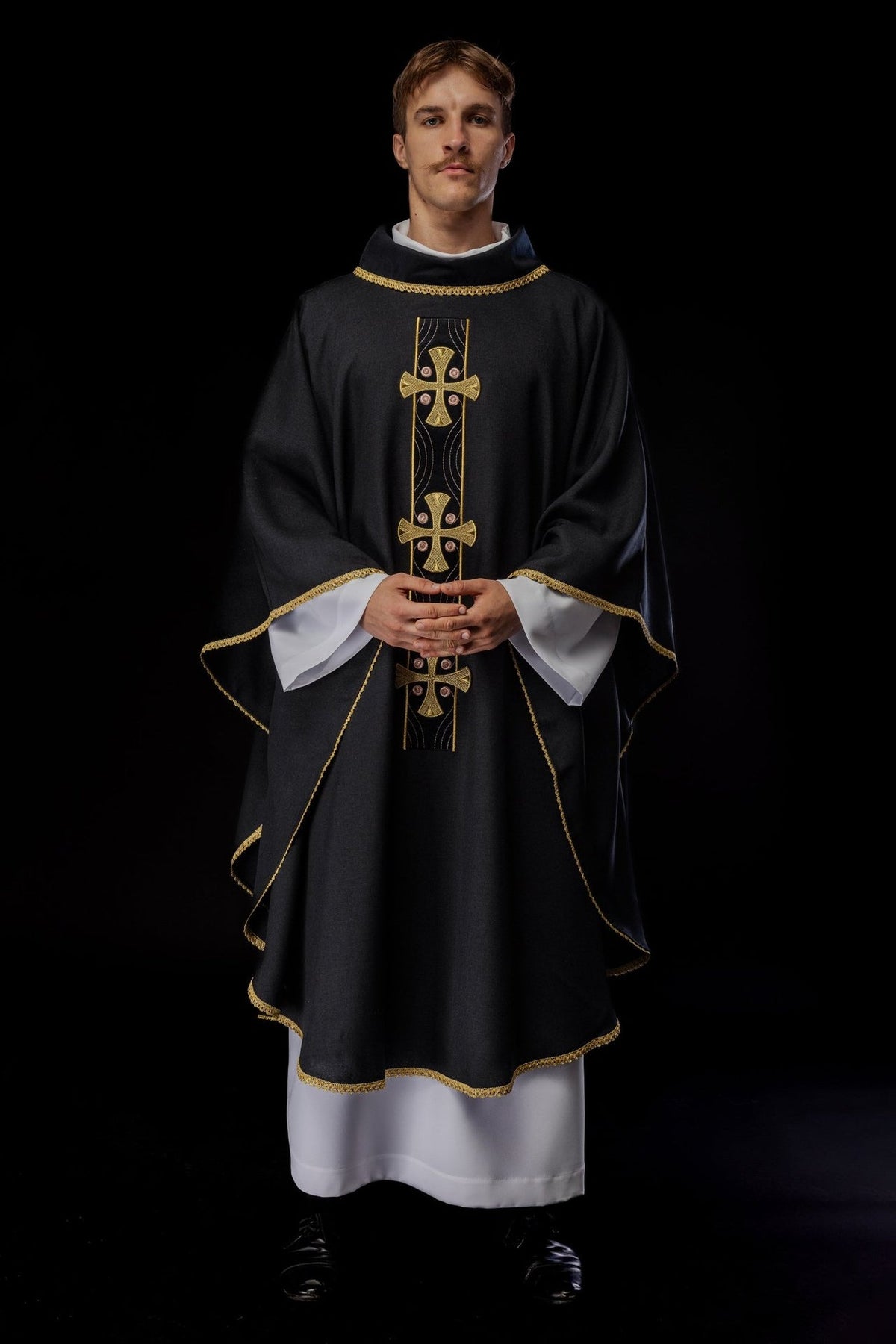 Black chasuble worn, full front view with embroidered gold crosses
