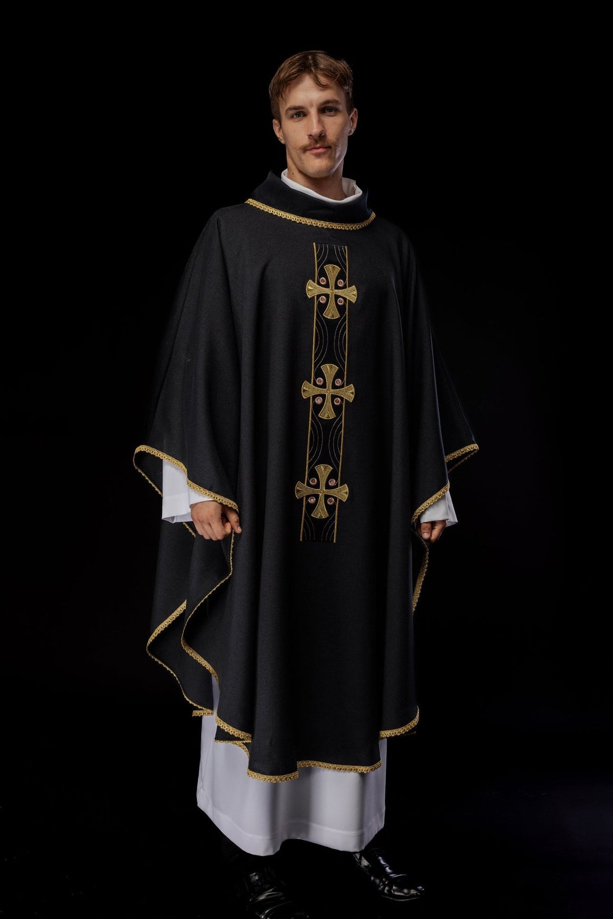 Black chasuble worn, front view with embroidered gold crosses