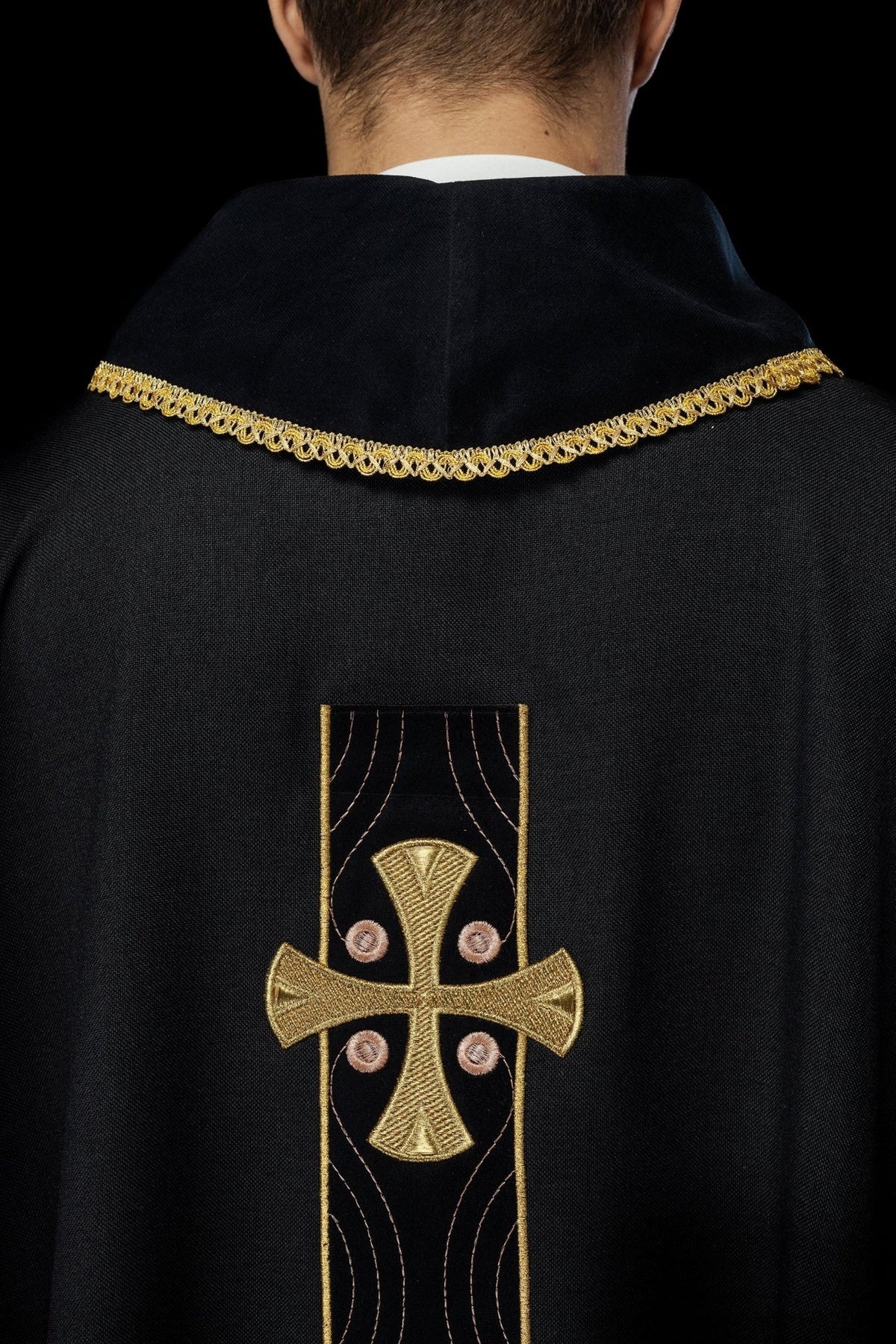 Black chasuble side detail with embroidered gold cross and collar trim
