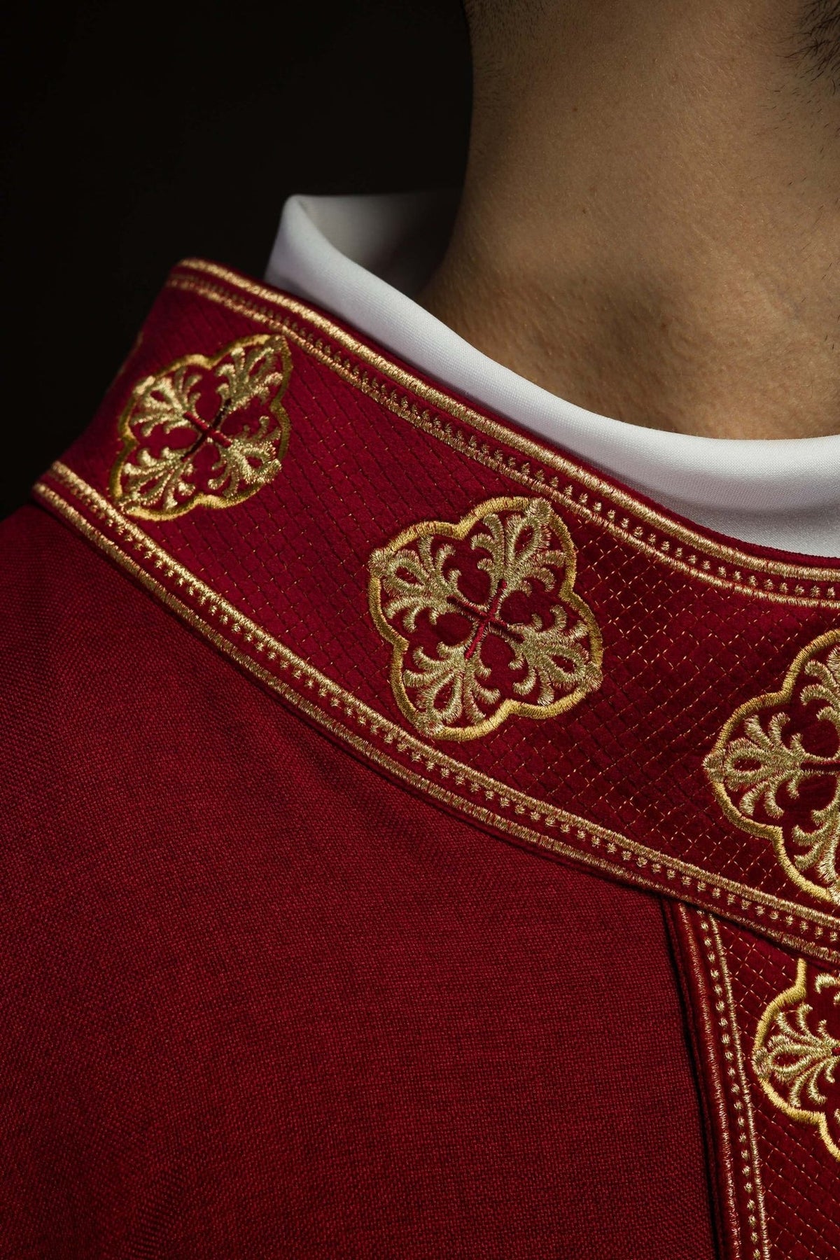 Red chasuble side view showing gold embroidered orphrey and white sleeve