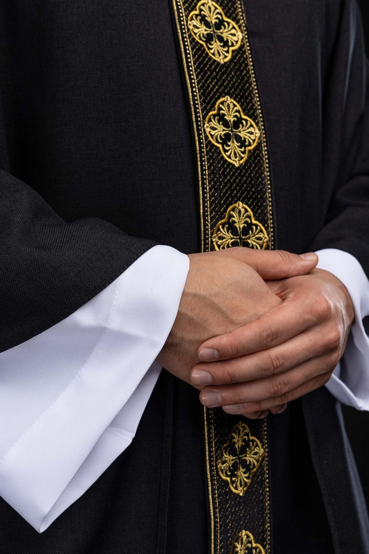 Black chasuble close-up showing gold embroidery on the front orphrey