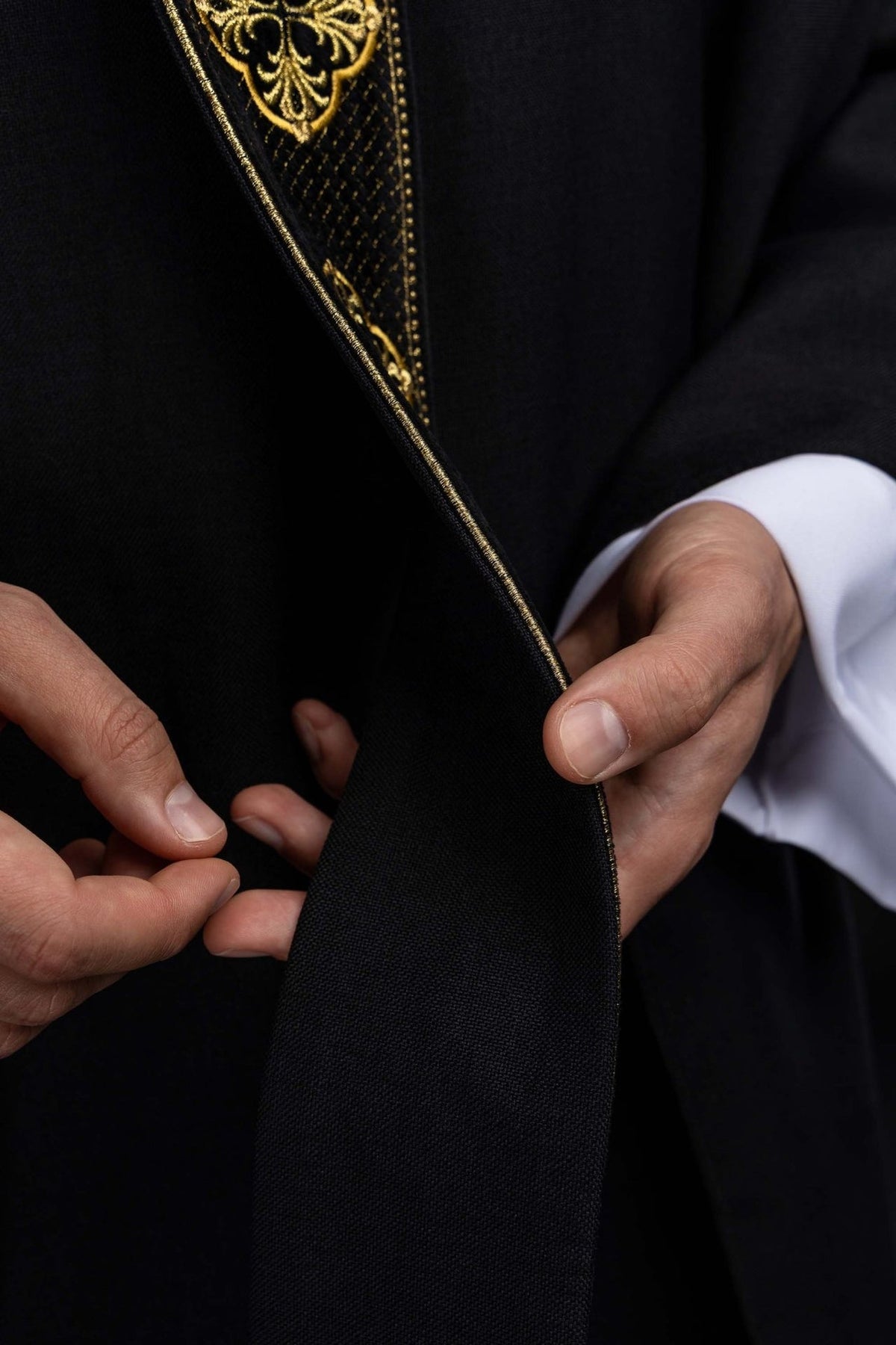 Black chasuble close-up showing the textured gold embroidery on the orphrey