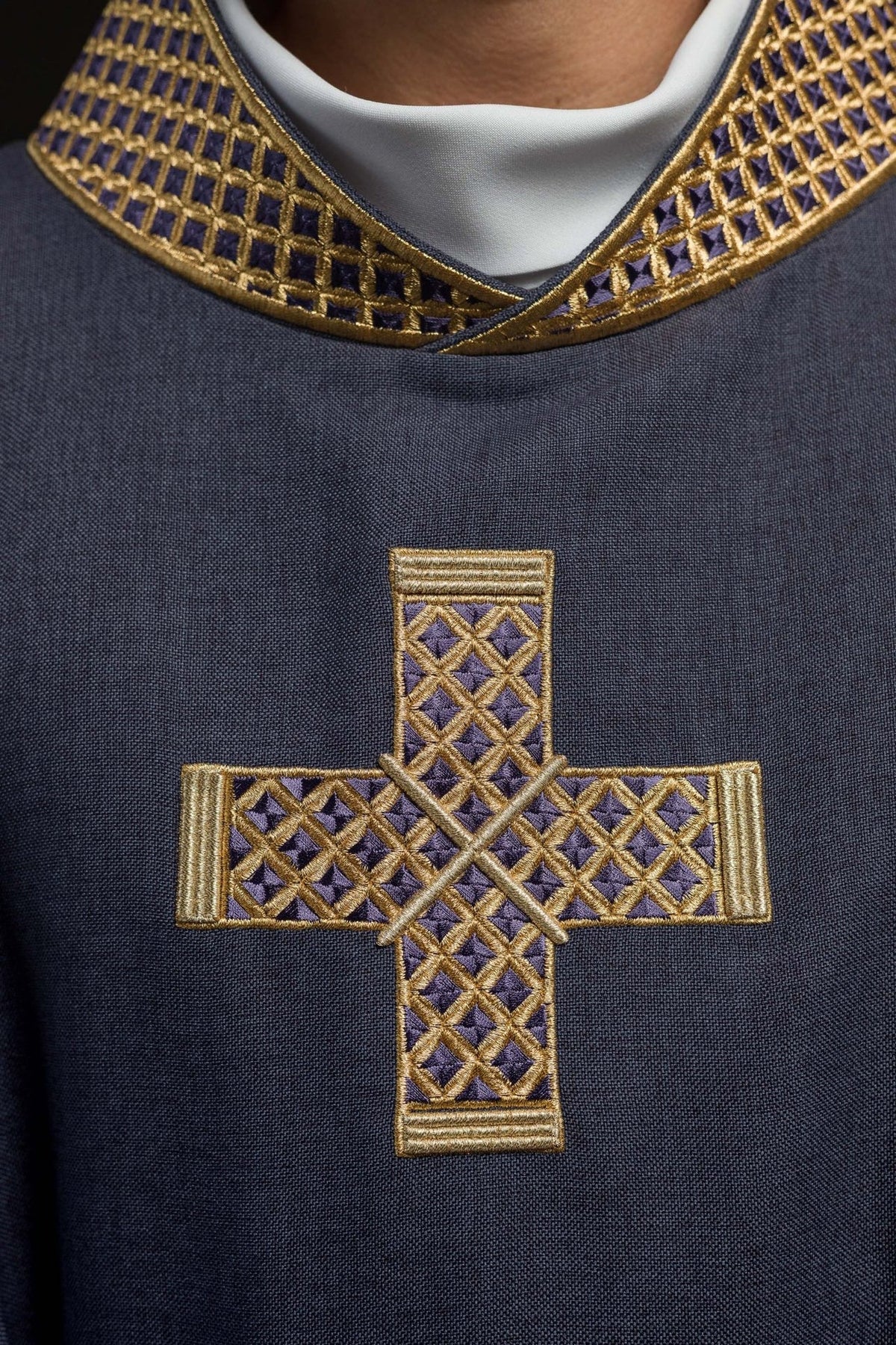 Purple chasuble close-up showing gold embroidered cross and collar