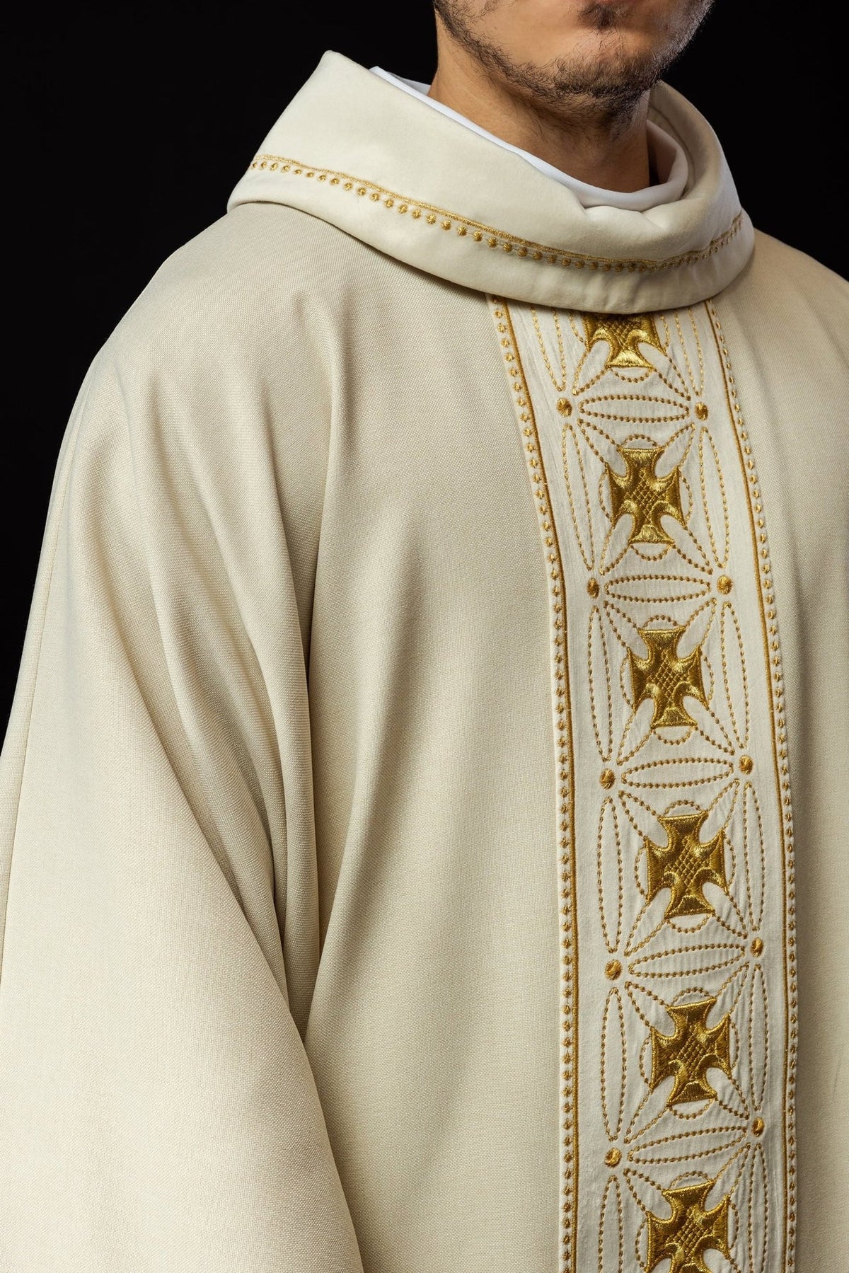 Ecru chasuble close-up showing gold embroidered crosses on the orphrey