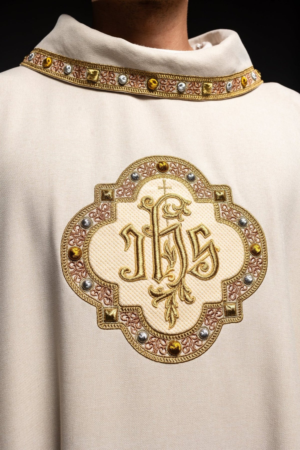 Ecru chasuble close-up showing IHS embroidery and jeweled trim