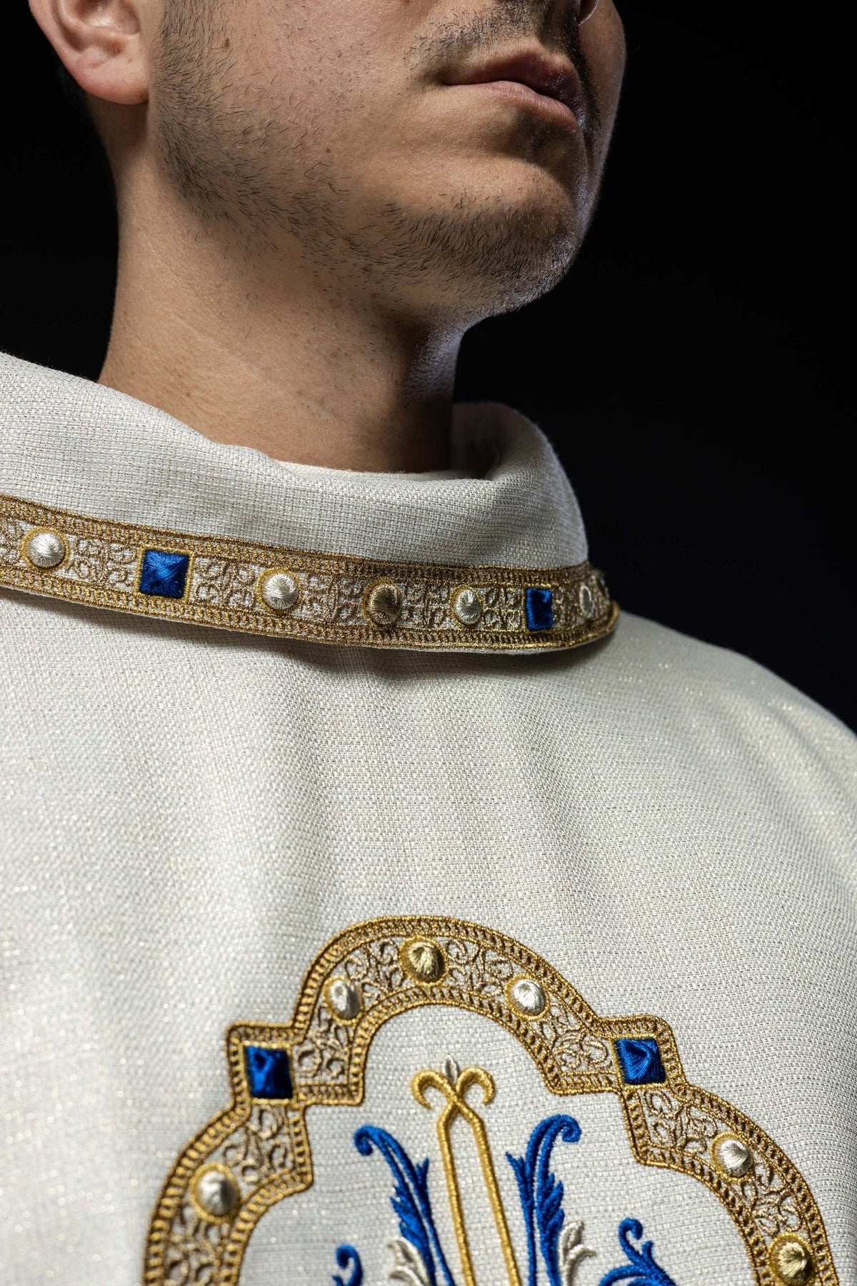 White chasuble close-up of embroidered Marian emblem in gold and blue