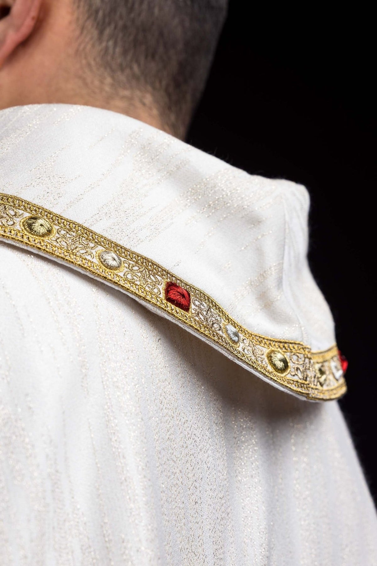 Chasuble close-up showing embroidered gold trim and white textured fabric