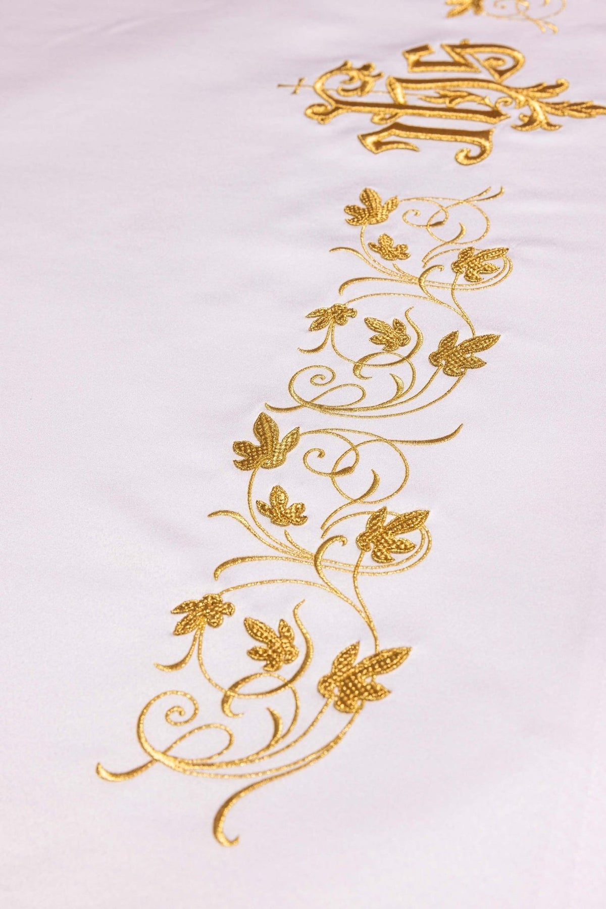 Altar cloth close-up showing a gold floral embroidery border on white fabric