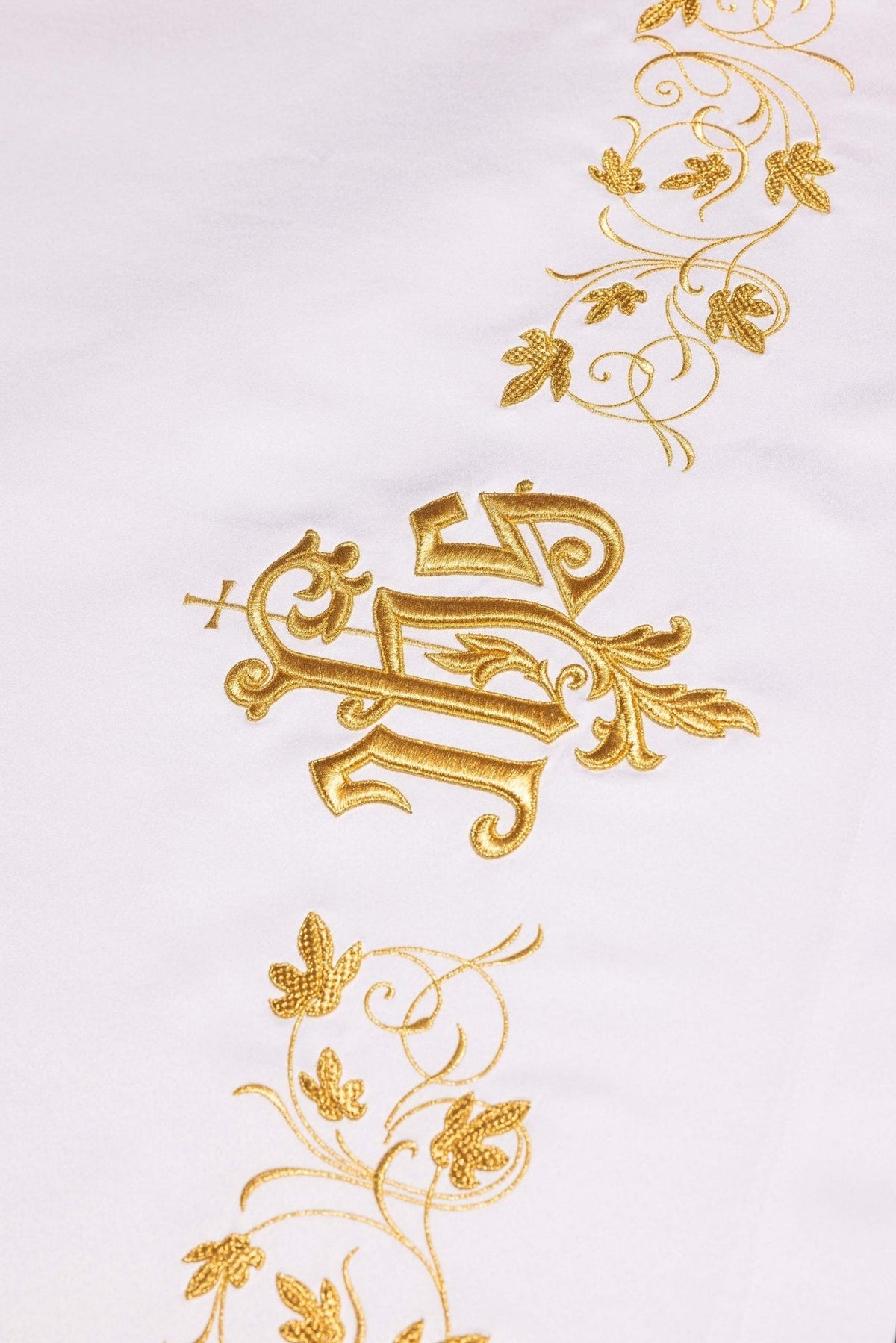 Altar cloth detail with repeated gold floral embroidery on white fabric