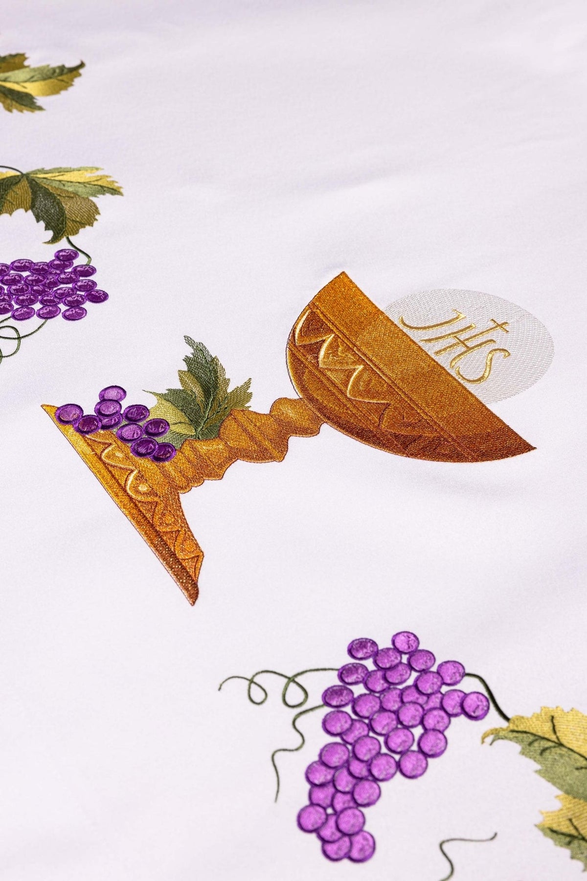 Altar cloth detail showing embroidered gold chalice with IHS monogram and purple grapes
