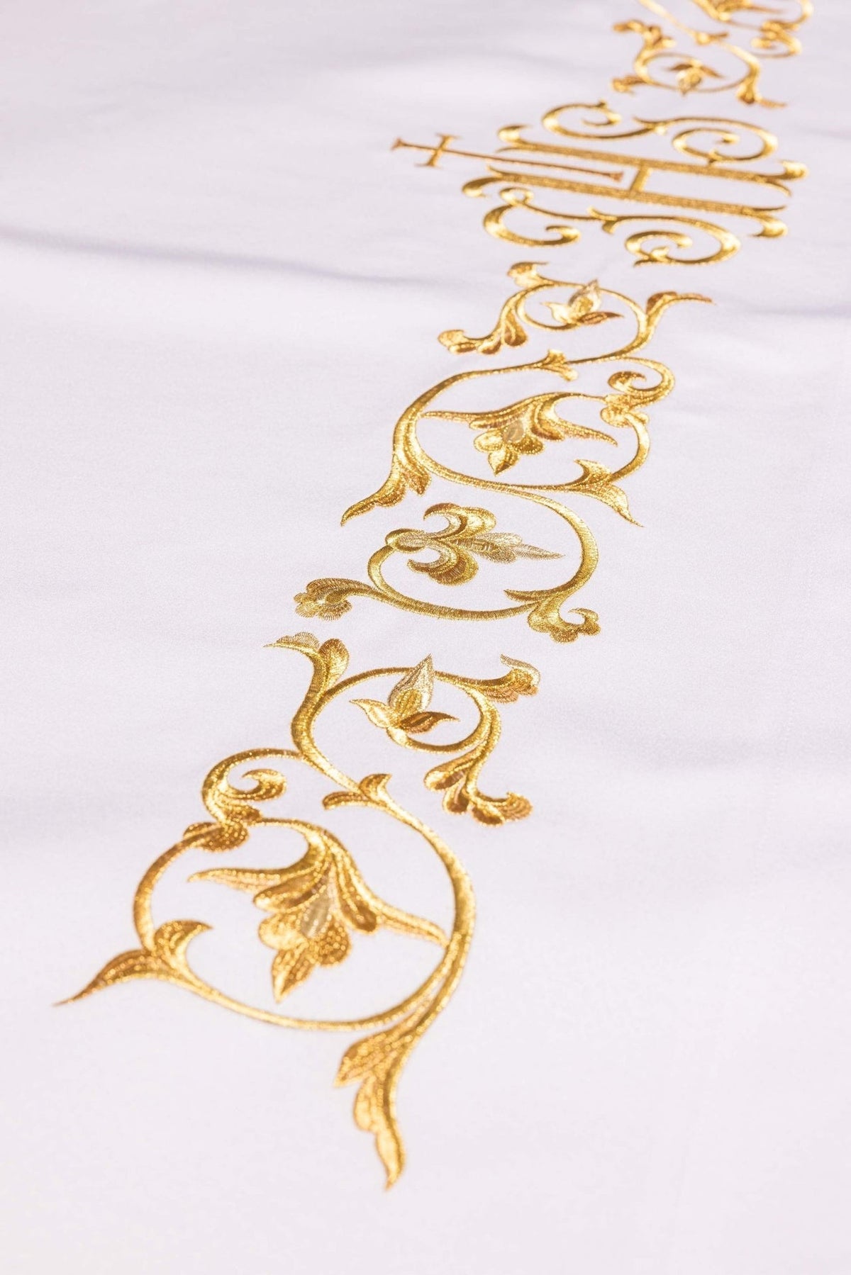 Altar cloth detail showing gold embroidery with IHS monogram and scrolling floral motifs