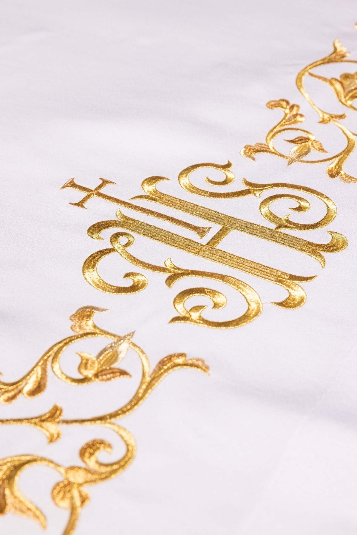 Altar cloth close-up of gold embroidered IHS monogram and surrounding ornamental scrollwork