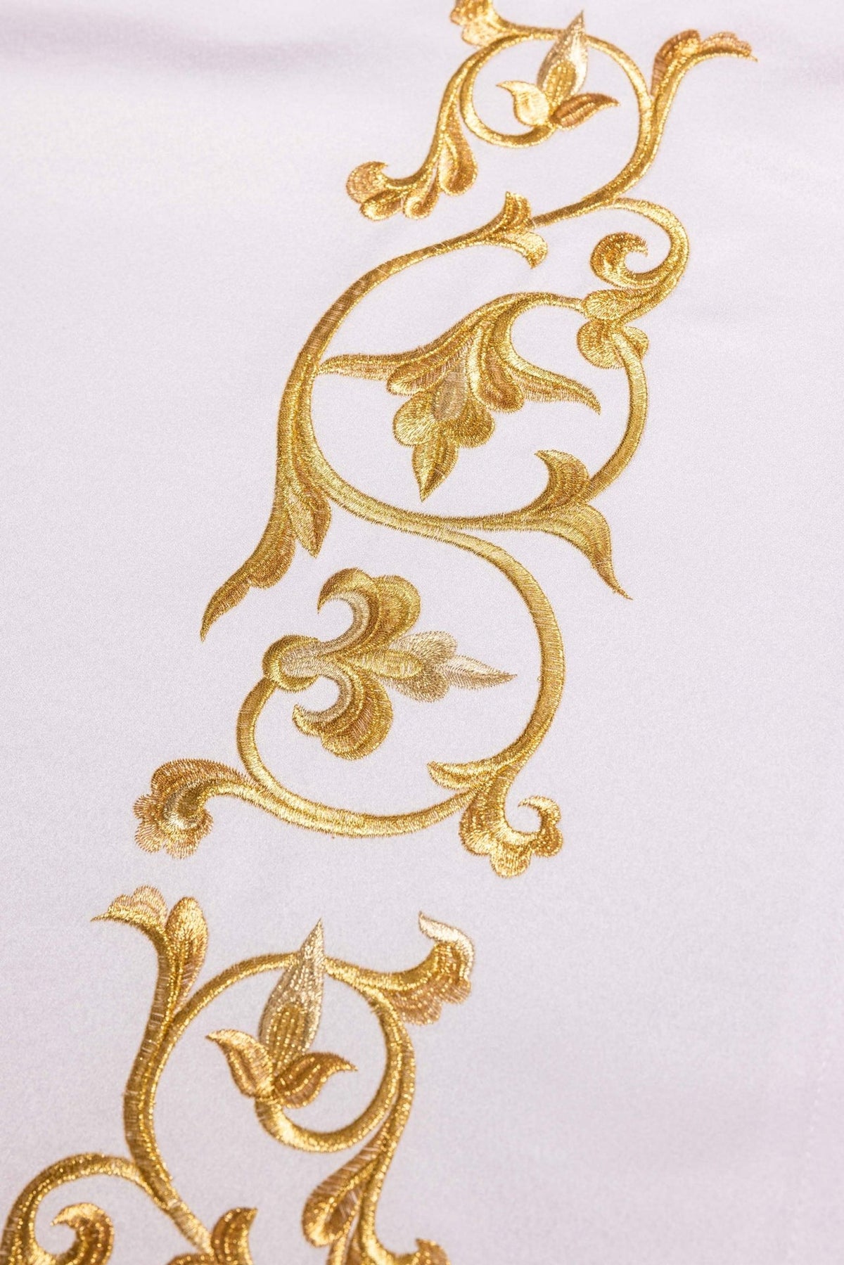 Altar cloth detail of gold floral embroidery and curling ornamental motifs on white fabric
