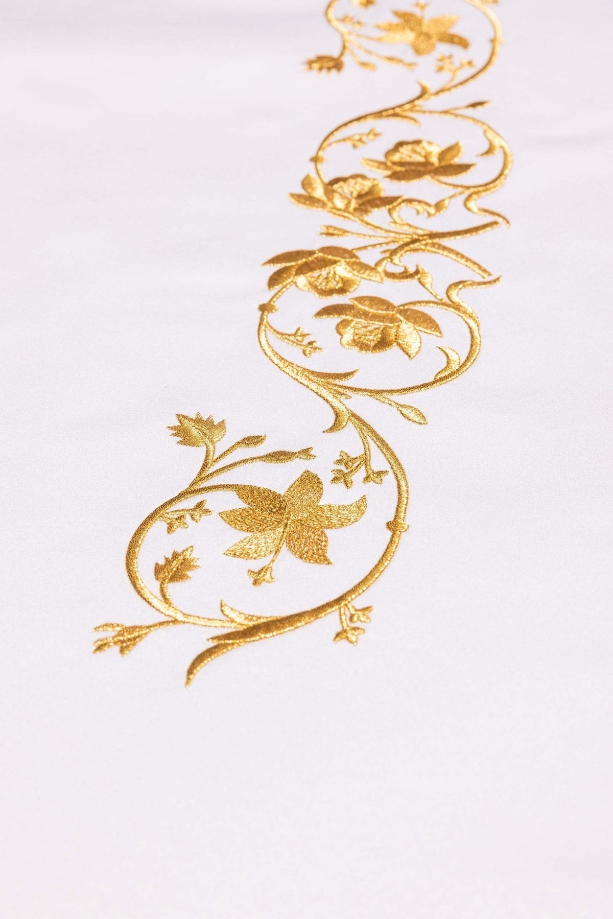 Altar cloth close-up showing gold embroidery of the Marian symbol and floral scrolls