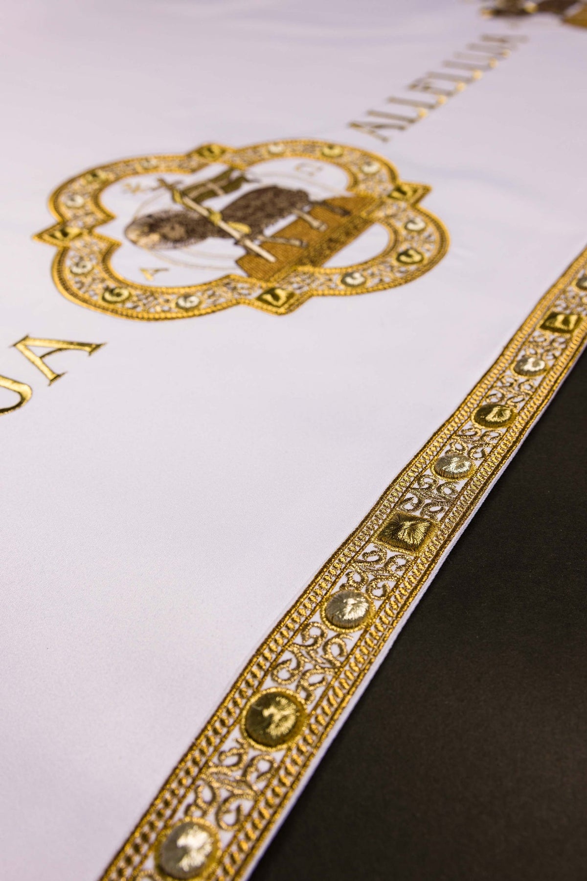 Altar cloth detail showing gold Agnus Dei embroidery and ornate border