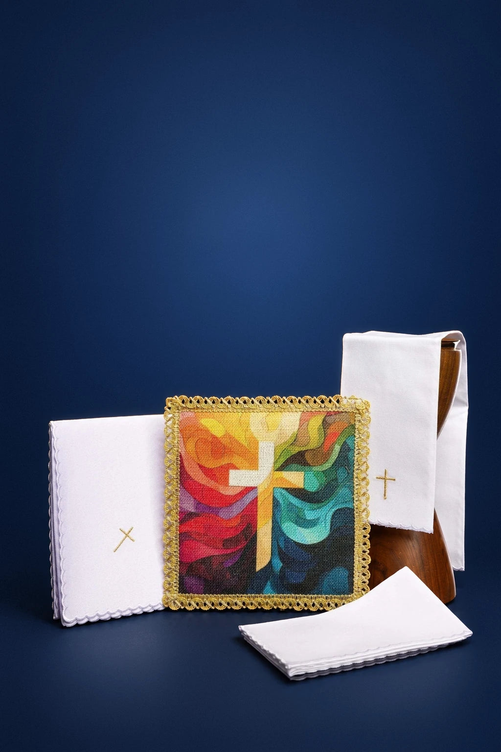 Set of white altar linens with gold cross embroidery and a colorful cross motif square cloth, front view