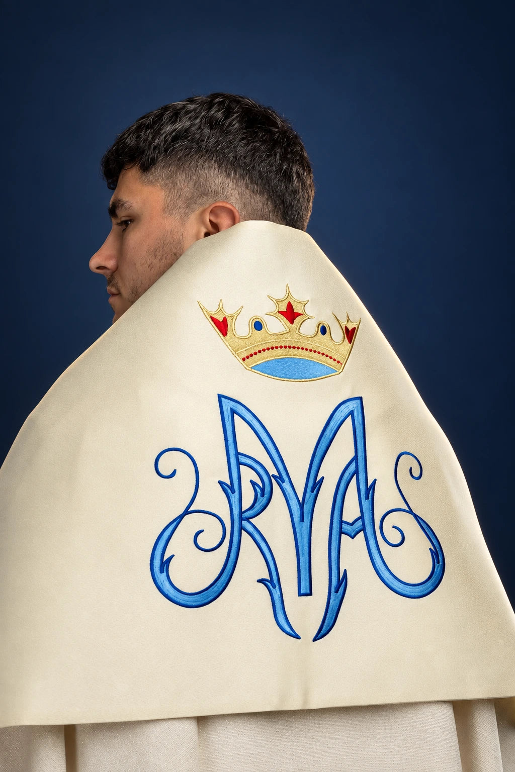 Side view of an ecru humeral veil with embroidered Marian monogram and crown motif