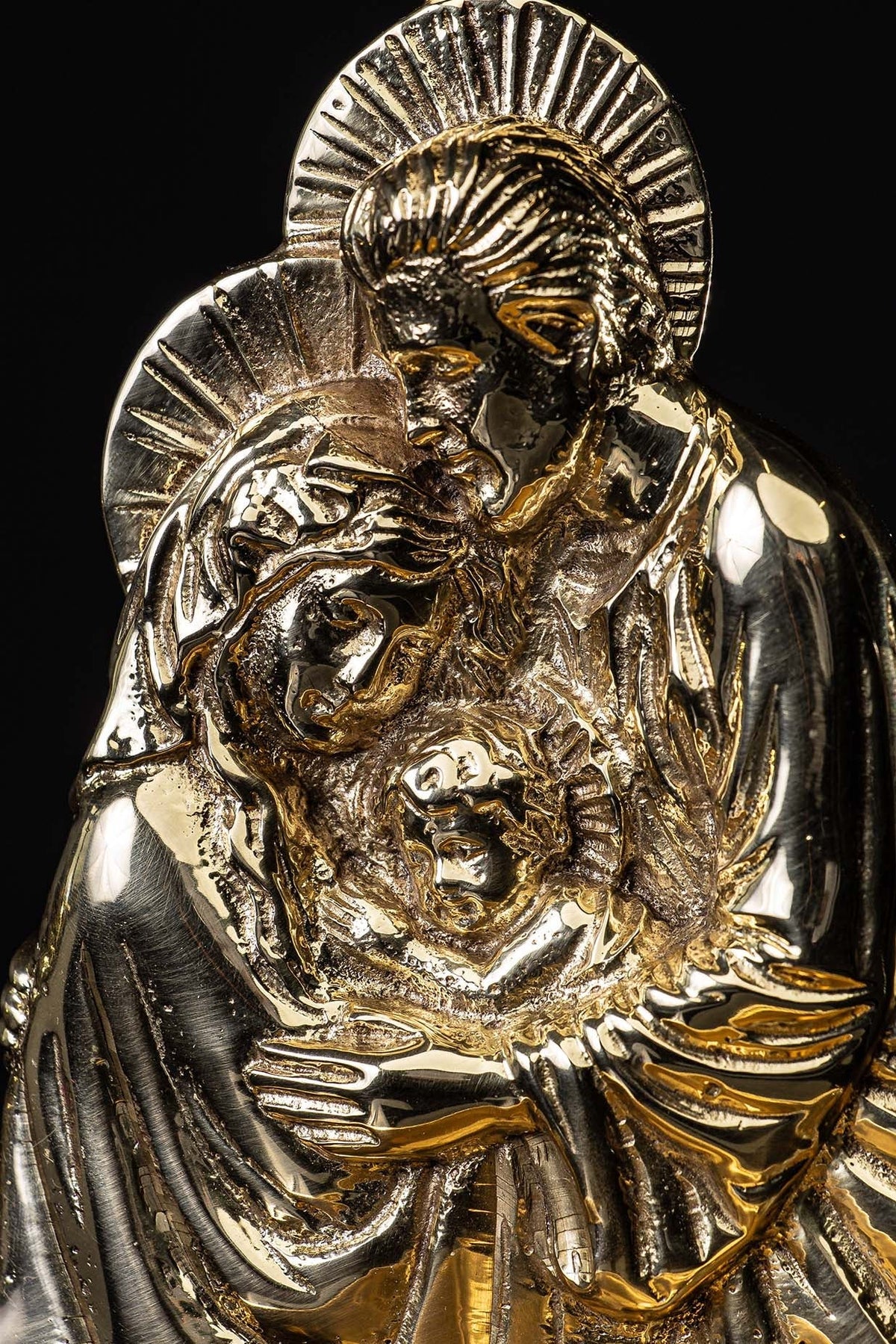Holy water font detail showing the brass Holy Family faces and radiant halos