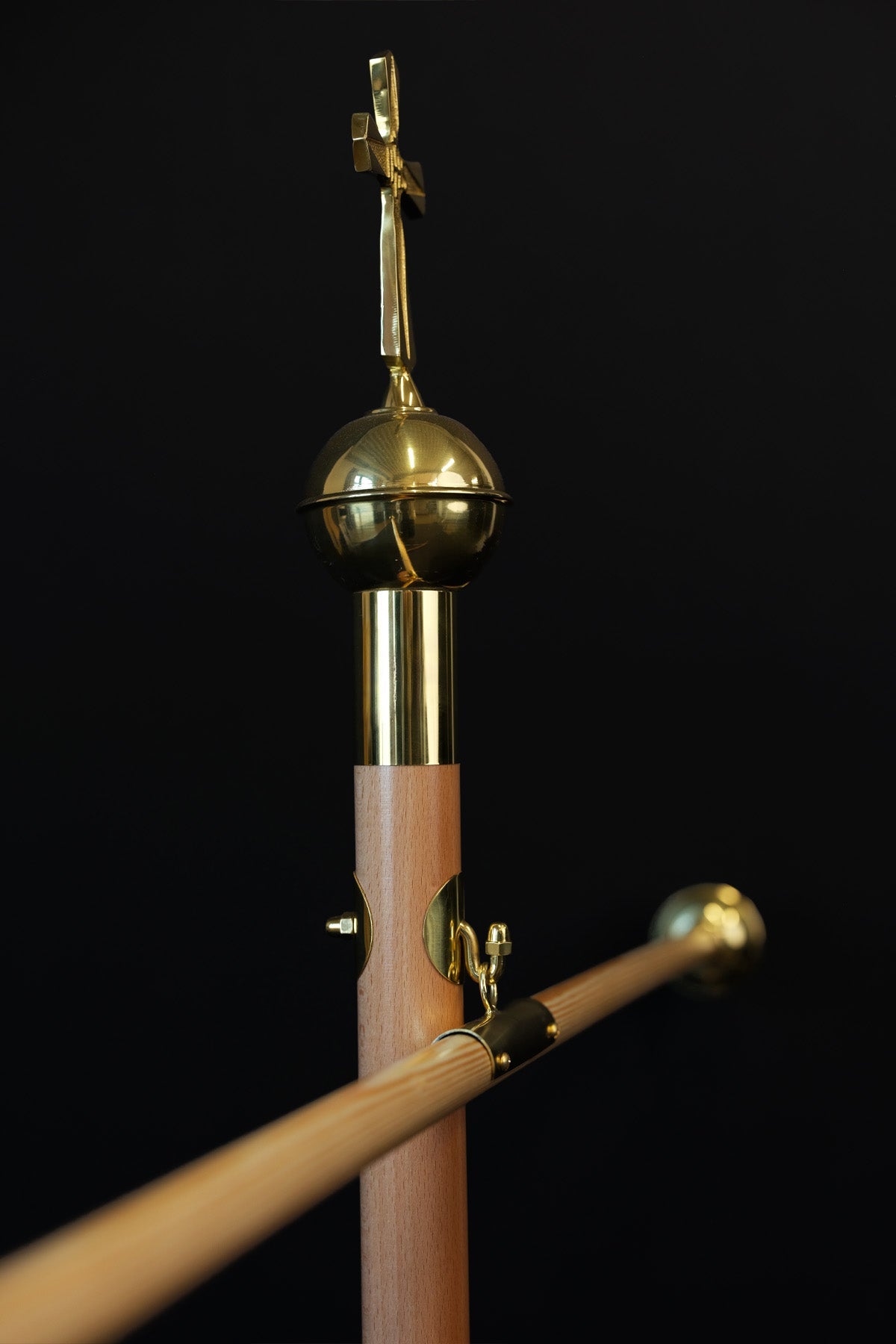 Light wood banner pole with decorative cross, angled close-up of gold fittings