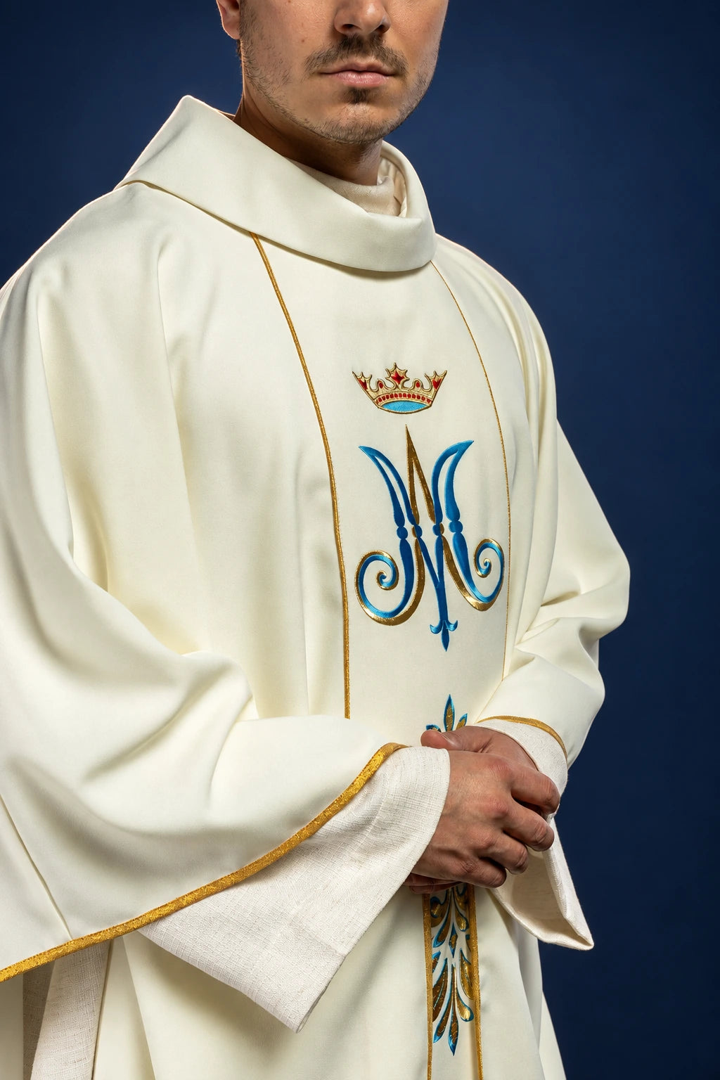 Three-quarter view of an ecru chasuble with Marian monogram, gold trim, and ornate cuff embroidery