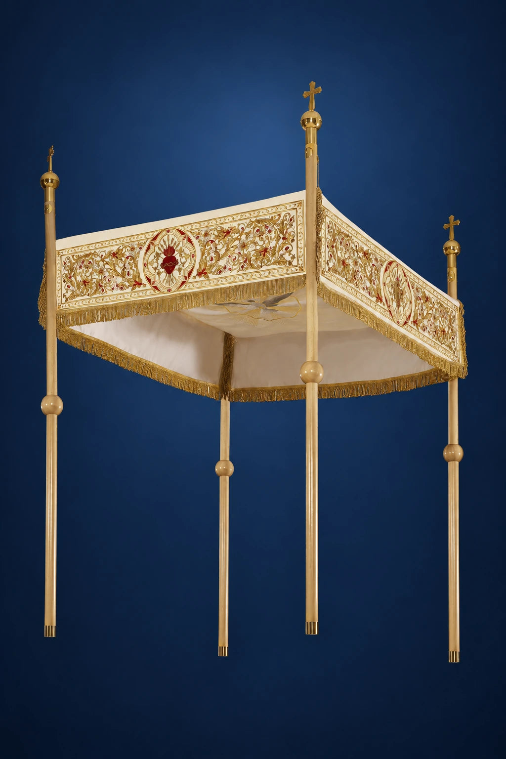 Three-quarter view of an ecru processional canopy with embroidered floral border and four gold poles with crosses