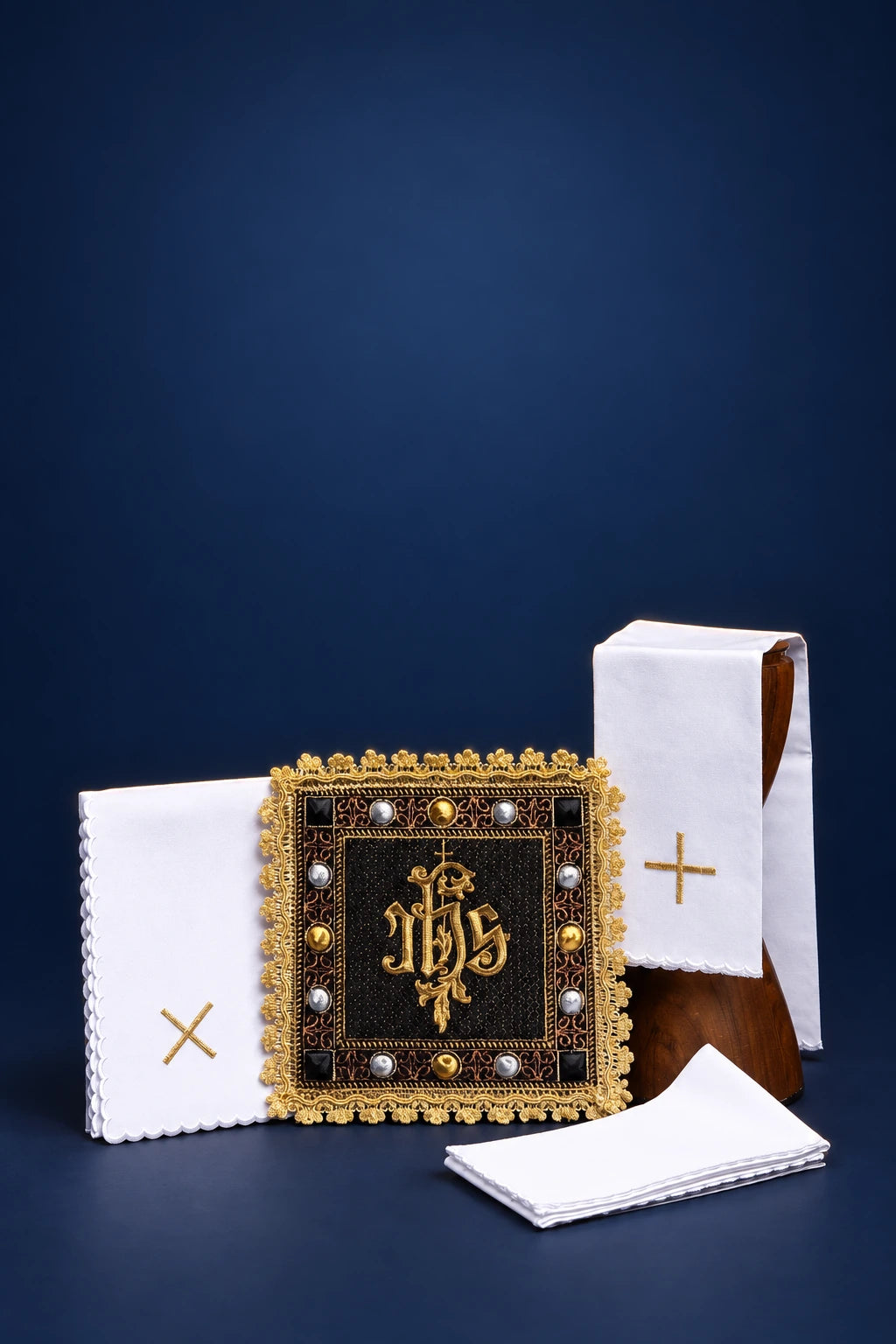 Velvet black altar linen set with embroidered IHS, shown with folded white linens and gold crosses