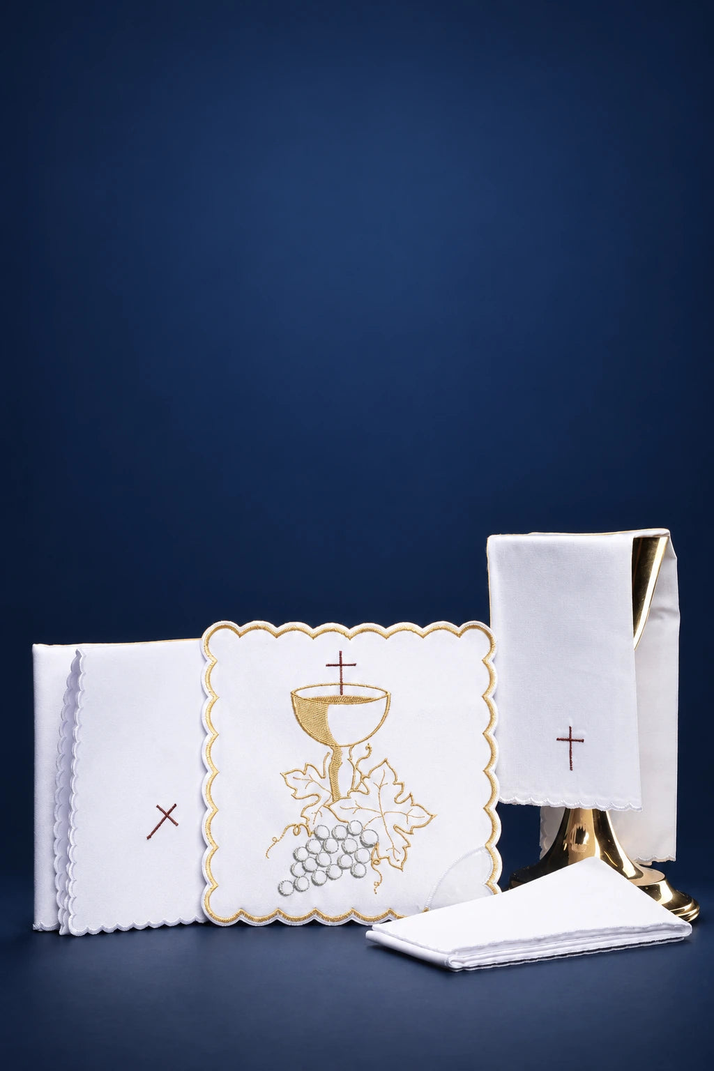 White altar linen set with gold Eucharistic embroidery and small red cross motifs, laid out flat